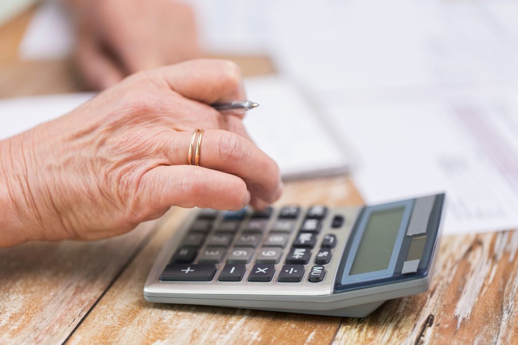 Senior woman using calculator to check paperwork